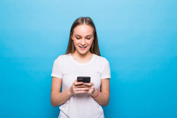 istock Contented smiling woman typing text message or scrolling through social networks using smartphone isolated over blue background 1253246983