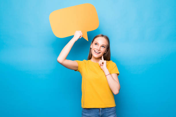 istock Young woman holding a speech bubble isolated on a blue background 1253247905