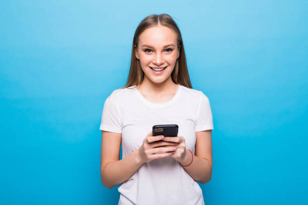 istock Contented smiling woman typing text message or scrolling through social networks using smartphone isolated over blue background 1253247967