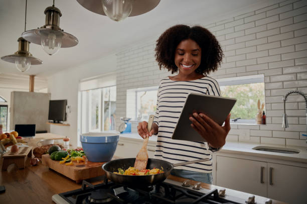 istock Young african woman watching recipe in digital tablet while cooking lunch in modern kitchen 1253249134