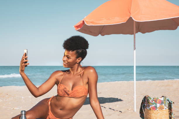 istock Woman sunbathing and texting on mobile on a sand beach 1253250644
