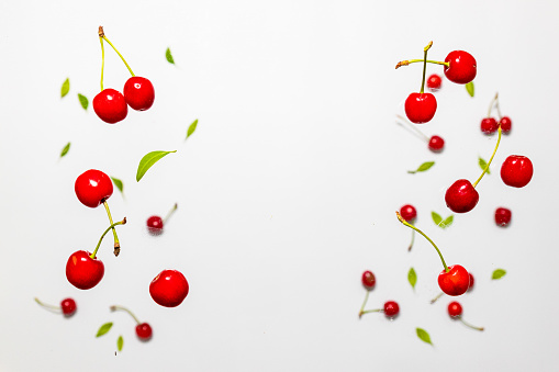Levitation of organic fresh ripe cherries pattern on a white background. Fall cherry with green leaves, healthy diet