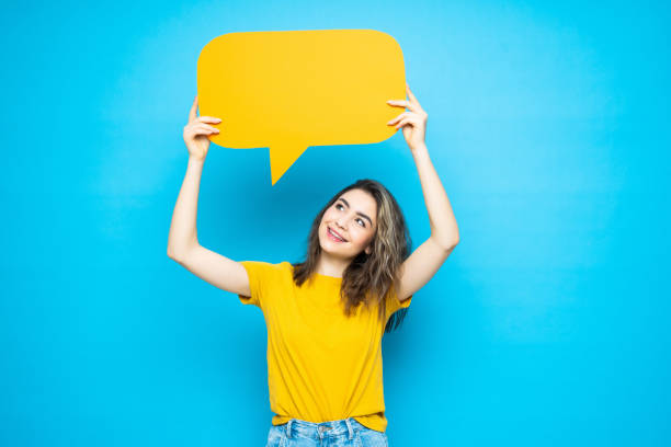 istock Young smile woman holding a speech bubble on a blue background 1253251193