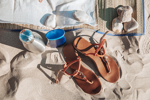 Sandals, water and sunscreen on the sand beach