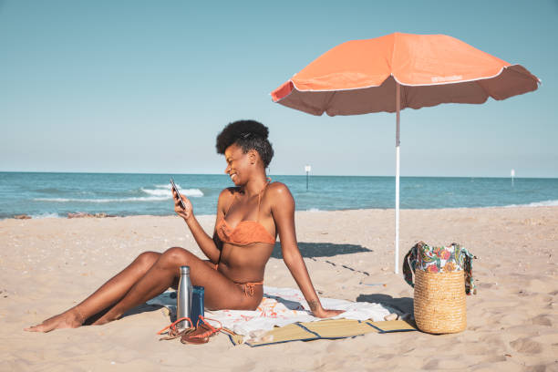 istock Woman sunbathing and texting on mobile on a sand beach 1253252662