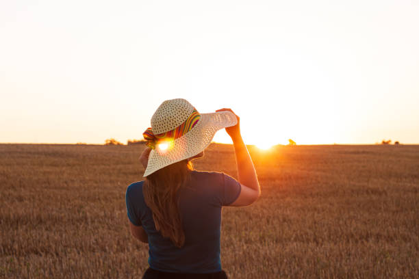 adorable young girl in summer wheat field with straw hat in hands. woman with long blonde hair on countryside sunset - homegrown produce wheat organic crop imagens e fotografias de stock