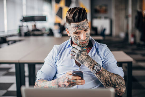 istock Modern tattooed businessman using smart phone in office 1253256457