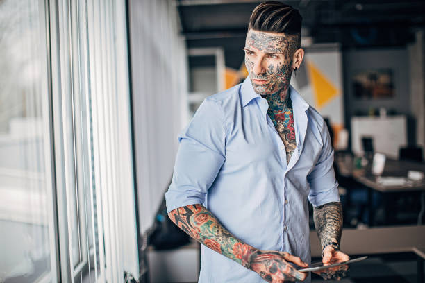 istock Modern tattooed businessman using digital tablet in office 1253256502