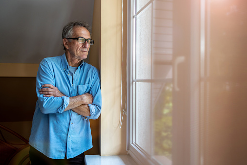 Senior man looking out of window at home