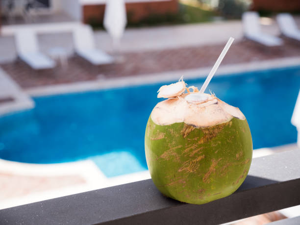 fruit de noix de coco avec la paille sur le rail de balcon - tourist resort apartment swimming pool caribbean photos et images de collection