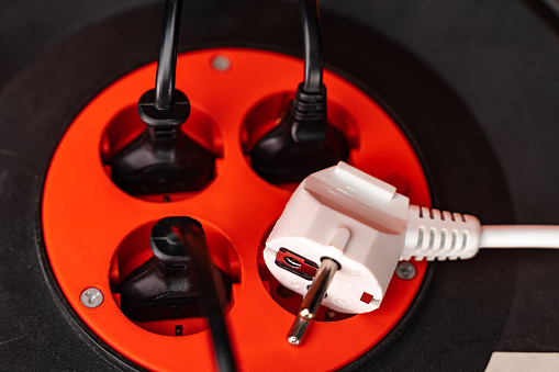 Multi plug and power cables. The scene is situated in controlled studio environment in front of orange background. Photo is taken with SONY AIII camera