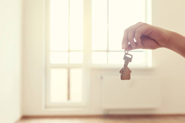 istock Home key in hand in apartment on empty room background 1253258734