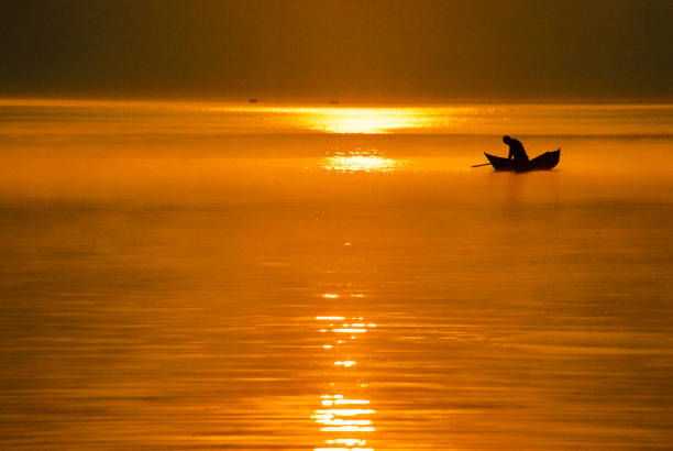 漁師と伝統的なボートとアフリカの淡水湖の上に美しい黄金の太陽 - lake victoria ストックフォトと画像