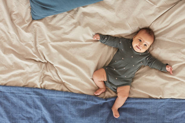 lindo mixto raza bebé acostado en la cama - onesie fotografías e imágenes de stock