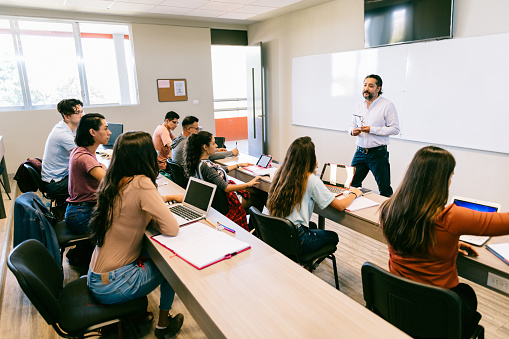 Teacher giving advice to diverse University Students in Classroom