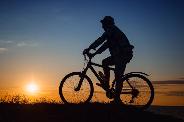 istock silhouette of a hipster man on a bicycle on sunset background 1253265752