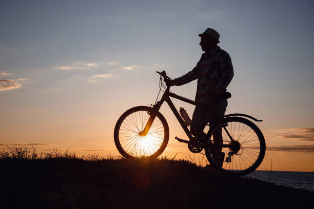 istock silhouette of a hipster man on a bicycle on sunset background 1253265854