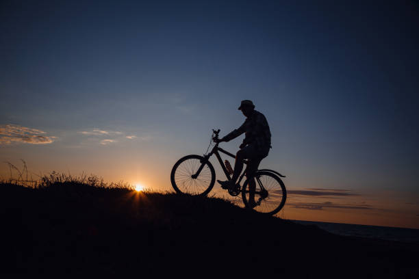 istock silhouette of a hipster man on a bicycle on sunset background 1253265909