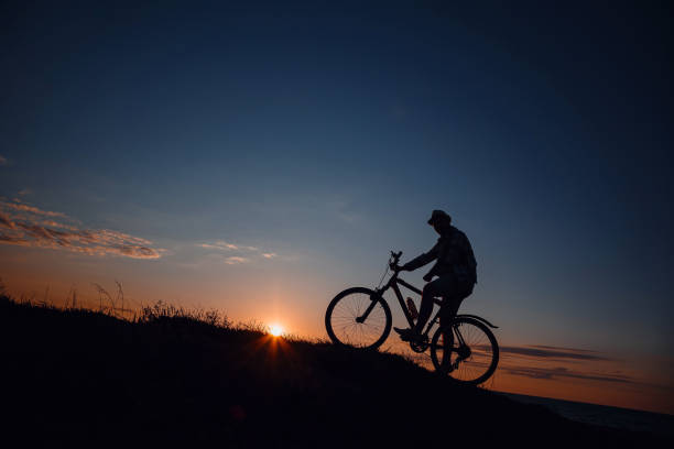 istock silhouette of a hipster man on a bicycle on sunset background 1253265921