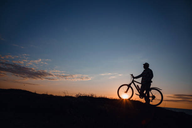 istock silhouette of a hipster man on a bicycle on sunset background 1253266042