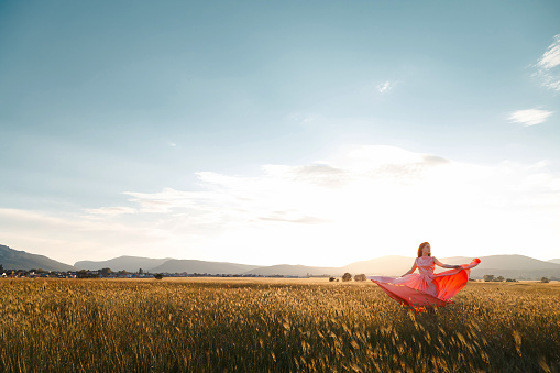 girl dancing in a field in a beautiful pink dress at sunset. ideal for advertising and photo sun shines bright and juicy