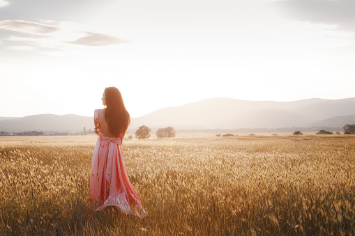 girl dancing in a field in a beautiful pink dress at sunset. ideal for advertising and photo sun shines bright and juicy