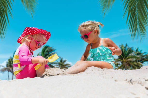 süße kleine mädchen spielen mit sand am tropischen strand - lifestyles child beach digging stock-fotos und bilder