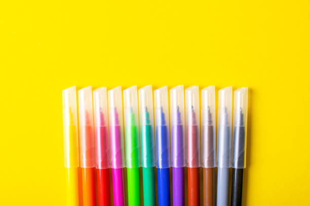 istock Multicolored felt-tip pens on bright yellow background. 1253269400
