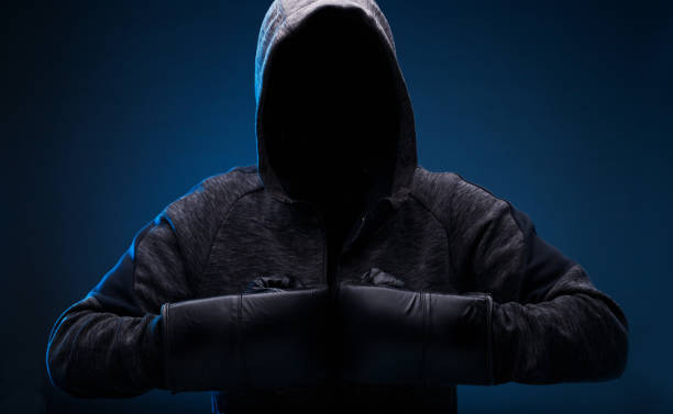 istock Dangerous hooded hacker. Internet, cyber crime, cyber attack, system breaking and malware concept. Anonymous. Dark background. Black minimalism. 1253269805