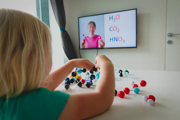 istock Kid learning remotely. Girl making experiments during online chemistry lesson at home 1253270950