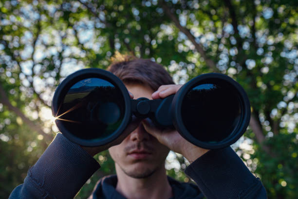 istock Explorer hiker young man in plaid shirt looking through binoculars 1253271098