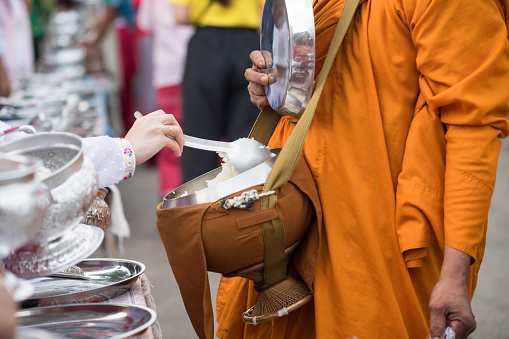 Mon people offer rice to Buddhist monk alms-bowl at morning in village, Sangkhla Buri, Kanchanaburi, Thailand. village religion lifestyle in early morning.
