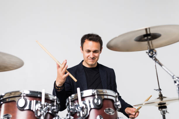 istock Young man play with drumsticks sitting at drums isolated on white background 1253278314