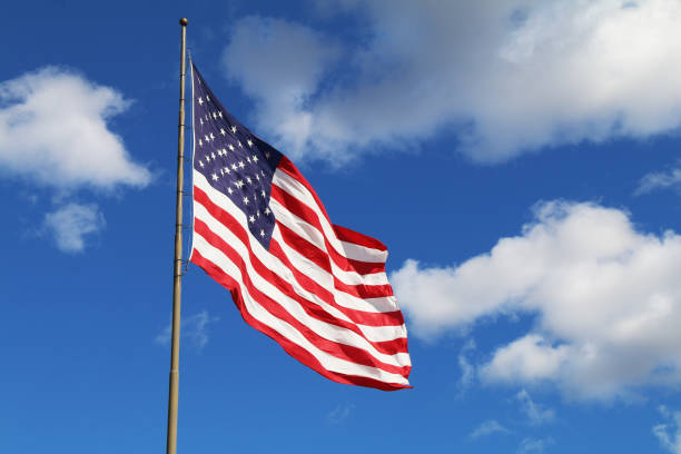 istock bright flowing waving american flag sunny day white clouds 1253279670