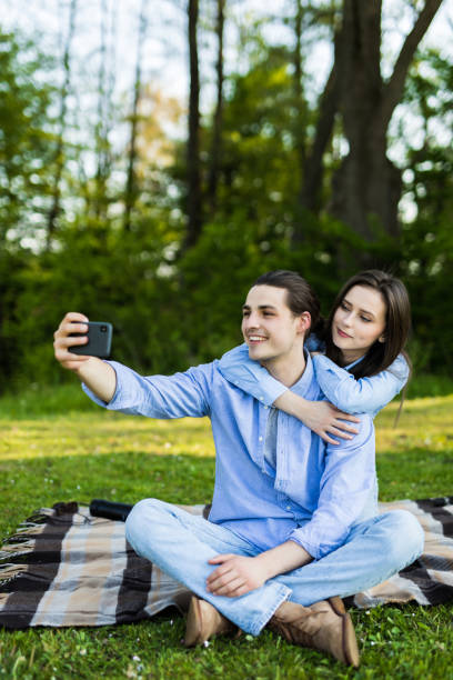 istock Loved young couple using mobile phone taking a selfie in the park 1253279770