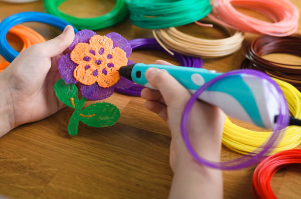 istock Child using 3D pen. Children hands making flower from colored ABS plastic. 1253279792
