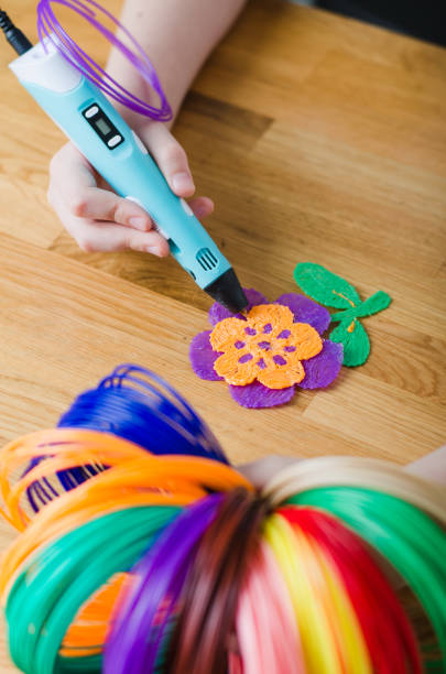 istock Child using 3D pen. Children hands making flower from colored ABS plastic. 1253279814