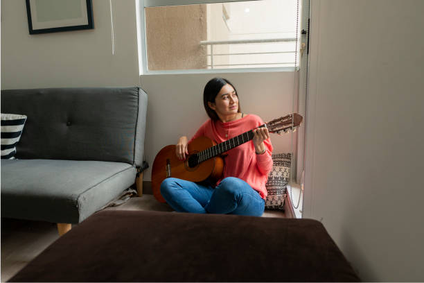 istock Woman Enjoys Playing Guitar From Her Home Window 1253279829