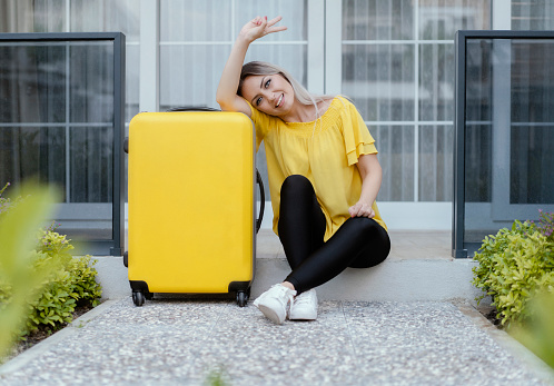 Young woman posing with her luggage, smiling and ready to go to travel
