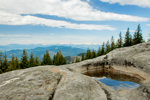 Magnificent panoramic view the coniferous forest on the mighty Carpathians Mountains and beautiful blue sky background. Beauty of wild virgin Ukrainian nature. Peacefulness. View from the mountain handwritten stone on the Carpathian mountains.