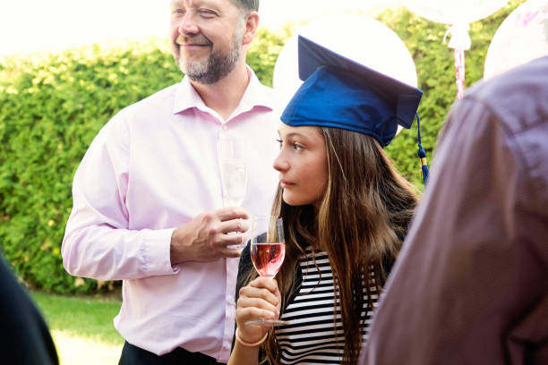 istock Father and daughter drinking for graduation party in backyard. 1253284563