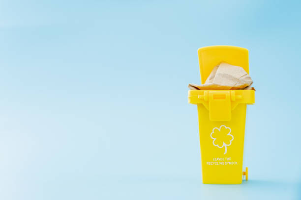 istock Large yellow trash can garbage bin with wheel on blue background 1253285129