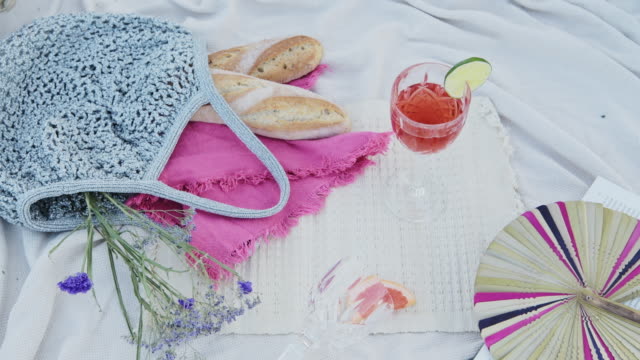 A Glass Of Rose Wine in a luxury romantic picnic date on a white blanket at the beach - Close Up Shot