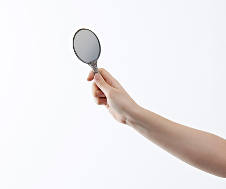 Woman holding a handheld make up mirror