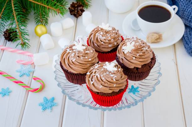 istock Chocolate cupcakes with cheese chocolate cream with a cup of coffee and marshmallows for Christmas and New Year on a white wooden background. 1253286973
