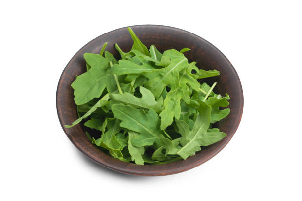 istock Fresh leaves of arugula in ceramic brown bowl isolated. 1253287391