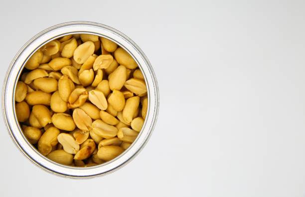 istock Top view close up of isolated open can with roasted salted peanuts, white background 1253287907