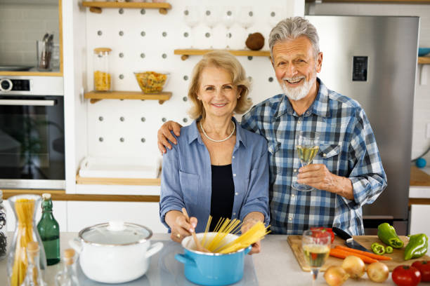 istock Senior couple in the kitchen toasting with white wine 1253291825