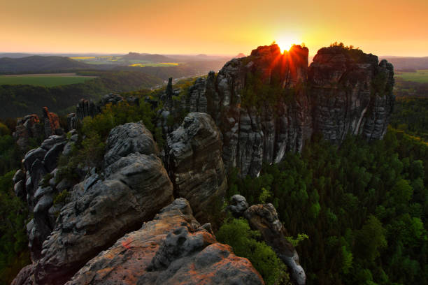 istock Schrammsteine, beautiful evening view over sandstone cliff into deep misty valley in Saxony Switzerland, foggy background, the fog is orange due to sunset, star sun on sky, Germany 1253293048