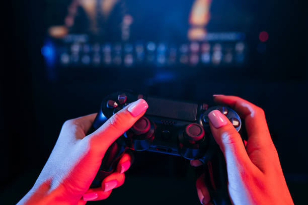 istock Close up female hands holding gamepad and playing videogames 1253294209